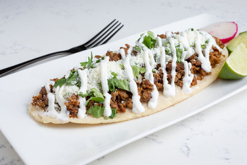 A view of a plate of Mexican huarache, in a restaurant or kitchen setting.