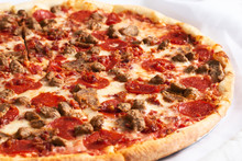 A View Of A Pizza Pie With Several Meat Toppings, In A Restaurant Or Kitchen Setting.