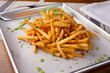 © DAVID - A closeup view of a tray of cajun style french fries in a restaurant or kitchen setting.