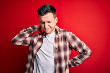 Young handsome caucasian man wearing casual modern shirt over red isolated background Suffering of neck ache injury, touching neck with hand, muscular pain