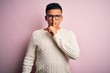 © Krakenimages.com - Young handsome latin man wearing white casual sweater and glasses over pink background asking to be quiet with finger on lips. Silence and secret concept.