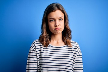 Young beautiful blonde girl wearing casual sweater standing over blue isolated background depressed and worry for distress, crying angry and afraid. Sad expression.