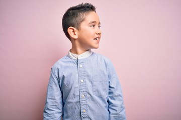 Poster - Young little boy kid wearing elegant shirt standing over pink isolated background looking away to side with smile on face, natural expression. Laughing confident.