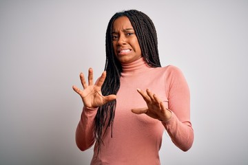 Sticker - Young african american woman standing casual and cool over white isolated background disgusted expression, displeased and fearful doing disgust face because aversion reaction. With hands raised