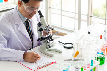 Asian male scientist look through the microscope in the laboratory.