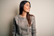 © Krakenimages.com - Young beautiful brunette woman wearing casual sweater over isolated white background looking away to side with smile on face, natural expression. Laughing confident.