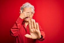 Senior Beautiful Grey-haired Woman Wearing Casual Shirt And Glasses Over Red Background Covering Eyes With Hands And Doing Stop Gesture With Sad And Fear Expression. Embarrassed And Negative Concept.