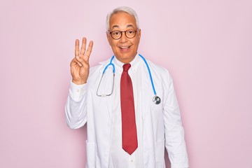 Wall Mural - Middle age senior grey-haired doctor man wearing stethoscope and professional medical coat showing and pointing up with fingers number three while smiling confident and happy.