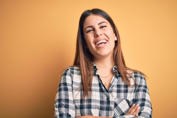 Young beautiful woman wearing casual shirt standing over isolated orange background happy face smiling with crossed arms looking at the camera. Positive person.