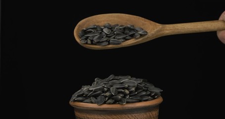 Wall Mural - Sunflower grains get enough sleep from a wooden spoon on a pile of seed in a clay bowl.