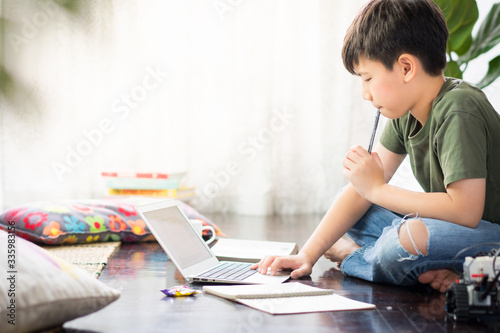Fotografía Smart looking Asian preteen boy sit crossed legs, holding pen against his lips,