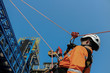Close up rope access, abseiling worker on high wear dresses and safety man with harness concept on steel structures success from work in site construction on blue sky background.