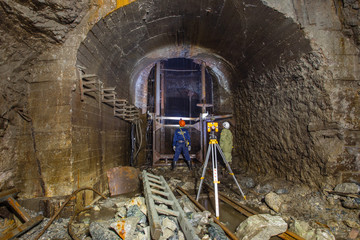 Miners mine surveyor at underground gold mine tunnel