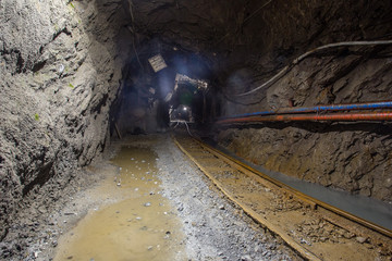 Underground gold mine shaft tunnel drift with rails and light