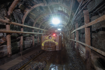 Electric locomotive in underground gold mine shaft tunnel