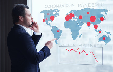 Wall Mural - Businessman talking on mobile looking at map of coronavirus pandemic and economy and financial markets collapse by corona virus. Staying at office home. Covid pandemic panic and unemployment crisis.