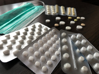 Medical face mask and pills on wooden background