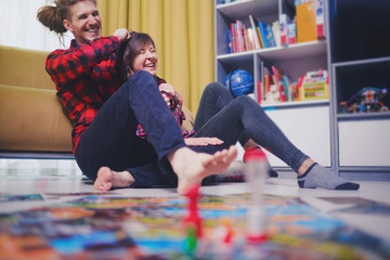 Wall Mural - Board game concept- friends spend time together. Board game field, figures, dice, coins and sandglass. Two people holding cards funny play and hug