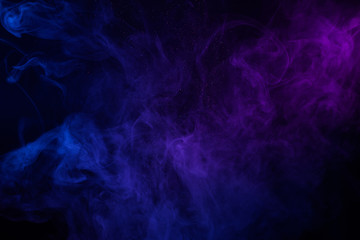 Colorful clouds of smoke and shiny dust on dark background