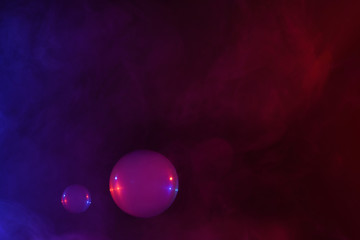 Wall Mural - two soap bubbles filled with smoke flowing over abstract colorful clouds of vapor with copy-space.