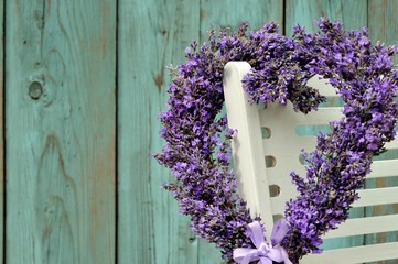 Wall Mural - Lavender wreath in the shape of a heart on white armchair on the blue old wooden background close-up
