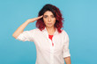 Yes sir! Portrait of responsible serious hipster woman with fancy red hair in white shirt saluting commander, listening order with obedient expression. indoor studio shot isolated on blue background
