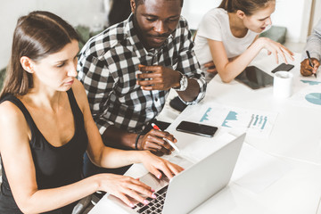 Wall Mural - A team of young office workers, businessmen with laptop working at the table, communicating together in an office. Corporate businessteam and manager in a meeting. coworking.