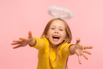 Wall Mural - Delighted happy little girl with angelic halo screaming with happiness and reaching into camera to hug tightly, extremely glad to see you. Daughter missed and running to parent. studio shot, isolated