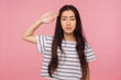Yes sir! Responsible serious girl with brunette hair in striped t-shirt giving salute with attentive look, listening to command, ready to obey order. indoor studio shot isolated on pink background
