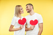 © GVS - Young couple in love holding big paper hearts in hands over studio background