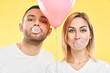 © GVS - Young couple blowing bubble with chewing gum and holding pink air balloon