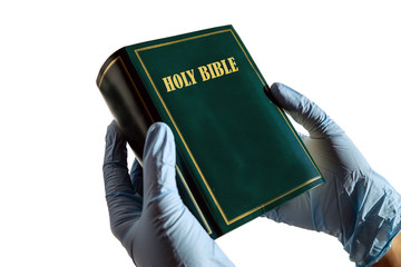 Person wearing plastic gloves holding a Bible