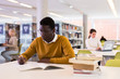 © JackF - Portrait of confident african-american male student working with book in public library