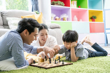 Time With Loved One Concept, Happy Asian Family Playing Chess Game In The Living Room Together.