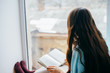 © aeroking - Young girl reading with book by the window