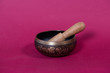 singing copper bowl with Sanskrit wooden stick on a red background