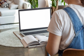 Girl sits with her back to a laptop with white screen, online education concept.