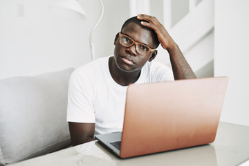 Wall Mural - man of African appearance at home in front of a laptop