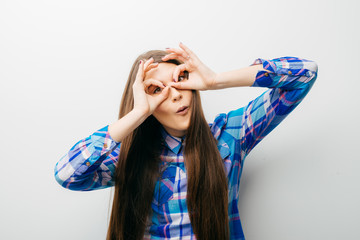 Wall Mural - Young happy woman holding her hands over her eyes as glasses and  looking through fingers