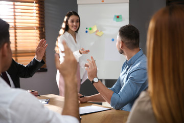 Canvas Print - People raising hands to ask questions at seminar in office