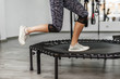 Fitness woman jumping on a mini trampolines, cropped photo