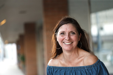 Happy and smiling middle aged 50+ woman having fun standing on sidewalk in urban area