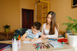 © Andrii - A young mother is doing homework with her son at home. Parents and training