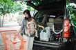 © Odua Images - mother put some groceries in to her car trunk while carrying her baby in parking lot