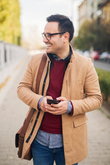 Wall Mural - Businessman with eyeglasses standing on the street holding phone.