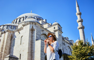 Wall Mural - Happy attractive woman tourist in hat, eating Simitci (a round bagel with sesame seeds) against the background of Suleymaniye mosque, Istanbul,Turkey. Religion and travel concept.