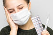 Woman with medical mask holding thermometer and pills in hands. Headache. Symptoms of corona virus disease.