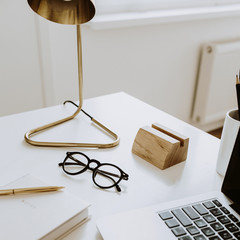 Minimalist workspace with laptop, notebook, lamp, glasses on white table. Working study. Freelancer, blogger, women's, girl boss office.