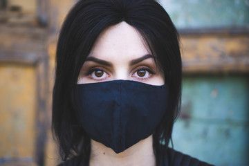 young girl  in a black protective medical mask respirator on a dark background. The concept of self-isolation, protection, Coronavirus, quarantine