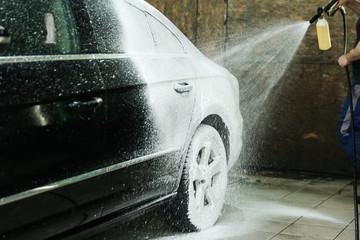 Wall Mural - car wash worker applies foam on the car. car washing close-up